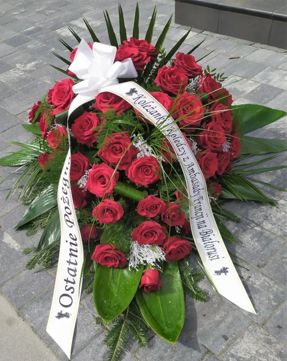 Duża wiązanka pogrzebowa z czerwonych róż z białą szarfą