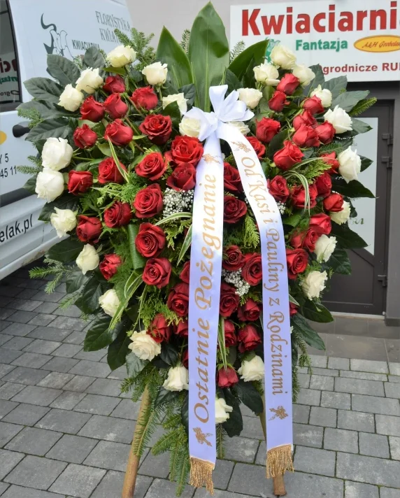 Wieniec pogrzebowy w kształcie serca z czerwonych i białych róż z gipsówką