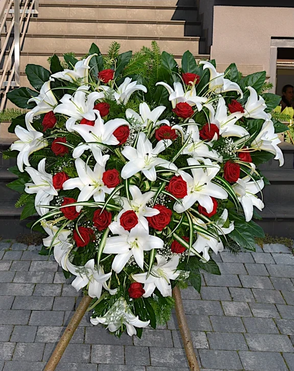 Wieniec pogrzebowy w kształcie serca z białych lilii i czerwonych róż